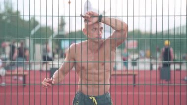 Atletik genç adam basketbol sahasında elinde bir topla dolaşıyor ve önüne bakıyor. Spor ve sağlık konsepti 