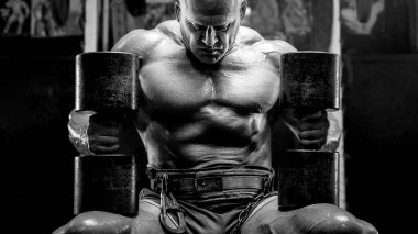 Vahşi ve kaslı güçlü vücut geliştirme sporcusu spor salonunda kaslarını şişiriyor. Spor ve sağlık geçmişi