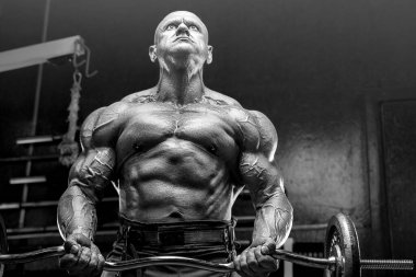 Vahşi ve kaslı güçlü vücut geliştirme sporcusu spor salonunda kaslarını şişiriyor. Spor ve sağlık geçmişi