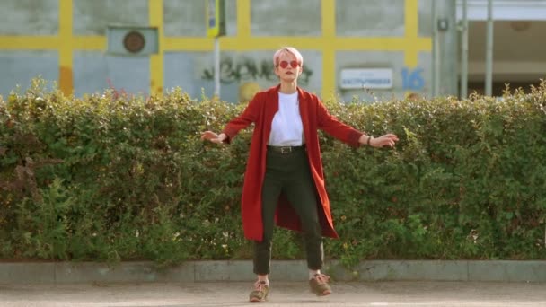 Kırmızı Paltolu Kırmızı Yuvarlak Gözlüklü Havalı Hippi Kız Sokaklarda Dans — Stok video