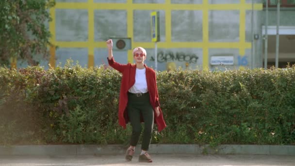 穿着红色外套 戴着红色圆形眼镜 在城市街道上跳舞的很酷的嬉皮士澳大利亚学生女孩 — 图库视频影像