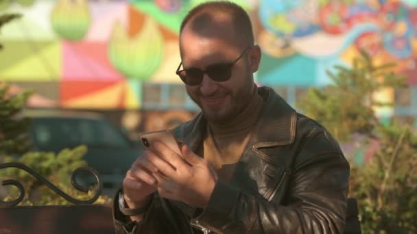 젊은이 시내의 야외에 스마트폰으로 문자를 있습니다 자켓을 잘생긴 코카서스 — 비디오