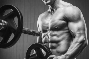 Spor salonunda kaslarını şişiren genç bir atletik. Spor ve sağlık geçmişi