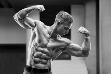 Spor salonunda kaslarını şişiren genç bir atletik. Spor ve sağlık geçmişi