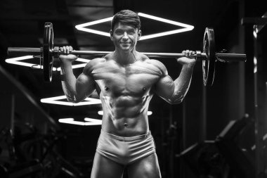 Spor salonunda kaslarını şişiren genç bir atletik. Spor ve sağlık geçmişi