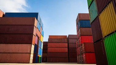 Bir depoya yığılmış büyük bir konteynır yığını var. Konteynırlar kırmızı, yeşil ve mavi olmak üzere farklı renklerdedir. Organizasyon ve verimlilik kavramı