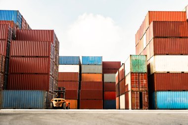 Yığının ortasında bir forklift olan büyük bir konteynır yığını üst üste yığılmış.