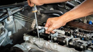 Bir tamirci bir araba motoru üzerinde çalışıyor. Odaklanma ve kararlılık kavramı. Tamirci motoru dikkatlice inceleyip tamir ediyor. Sahne, tamircinin yetenekli olduğunu gösteriyor.