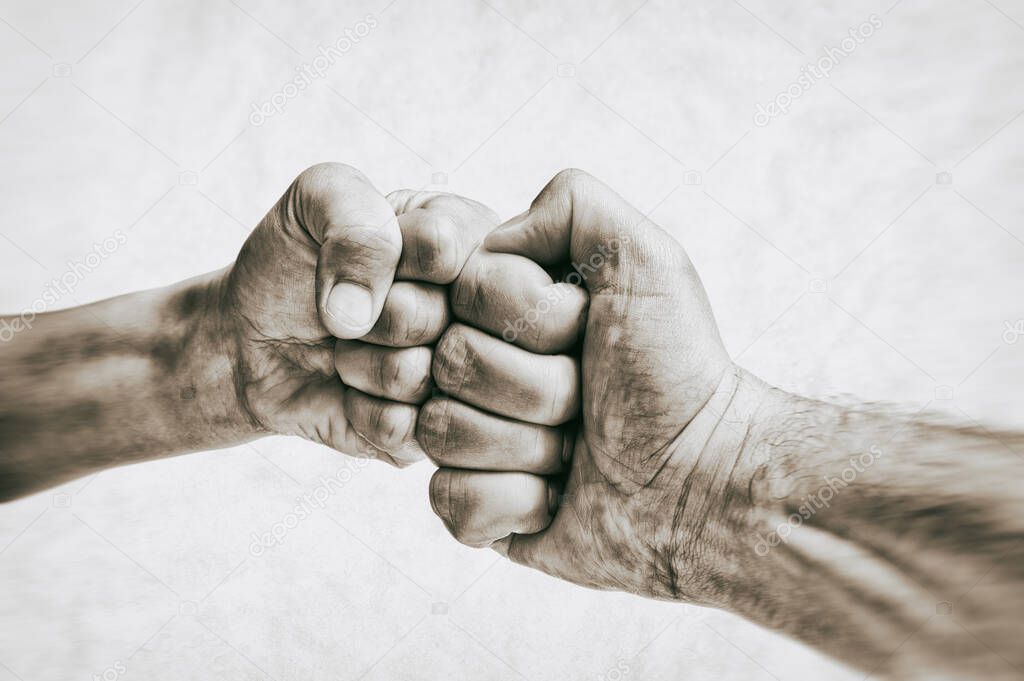 Clash of two fists on toned background. Concept of confrontation, fight, domestic violence. Black and white.