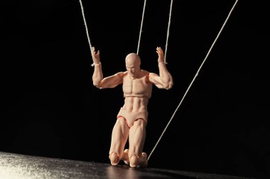 Kontrol kavramı. Marionette siyah arka planda dizlerinin üstünde.