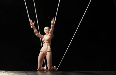 Kontrol kavramı. Marionette siyah arka planda dizlerinin üstünde.