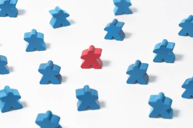 Oyuncak kırmızı ahşap bir insan figürü. Diğerlerinin mavi figürleri. İşe alım, yetenek yönetimi.