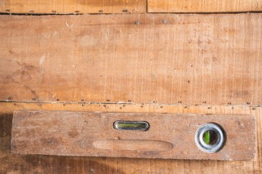 Eski ahşap bir kat, ahşap bir uçak, kerpeten ve tesisat hattı gibi antika inşaat aletleri izole edilir ve kahverengi ahşap bir duvarda antika bir tılsım sergilenir..