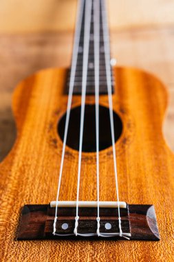 Beyaz ahşap telli klasik kahverengi akustik ukulele, caz ve rock konserine hazır bir folk müzik enstrümanı gibi ahşap bir masanın üzerinde duruyor.