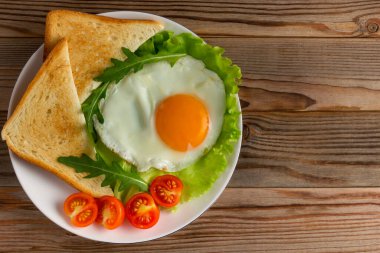 Domatesli sahanda yumurta, salata, roka ve ahşap kırsal arka planda üçgen tost.