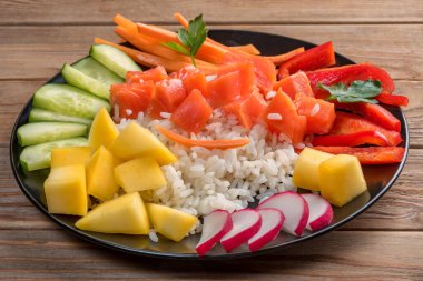 Hawaii 'den tahta arka planda siyah tabakta Poke salatası. Kapatın. Yumuşak odaklanma. Hazırlamak için sadece pilav, somon ve sebze alın..