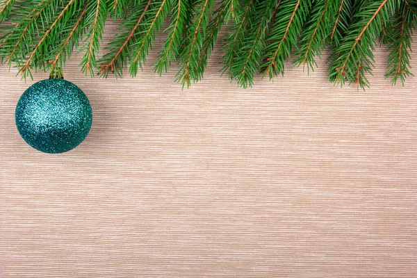 Green Christmas ball on a textile background with snow fir tree. Top view, space for your text
