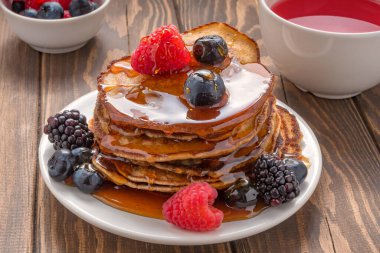 Balla kaplanmış krep, ahşap arka planda yabanmersini ve çilek. Yakın çekim. Yumuşak odak.