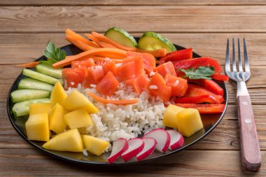 Hawaii 'den tahta arka planda kırsal çatalla siyah tabakta Poke salatası. Kapatın. Yumuşak odaklanma. Hazırlamak için sadece pilav, somon ve herhangi bir sebze al.