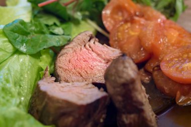 Izgara biftek, domates ve yeşil salata. Yumuşak odak.