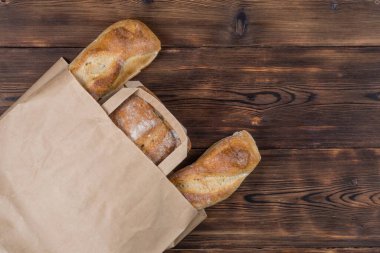 Ahşap arka planda, sıfır atık tekstil torbasındaki ekmeğin üst görüntüsü. Kopyalama alanı ile.