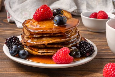 Balla kaplanmış krep, ahşap arka planda yabanmersini ve çilek. Yakın çekim. Yumuşak odak.