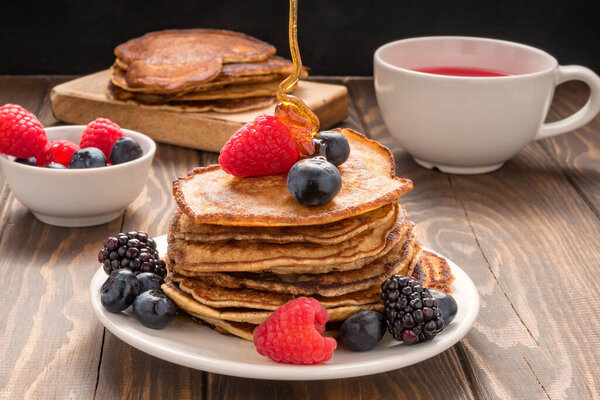 Выливание меда на блины с черникой и клубникой и чашкой красного сока