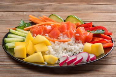 Hawaii 'den tahta arka planda siyah tabakta Poke salatası. Kapatın. Yumuşak odaklanma. Hazırlamak için sadece pilav, somon ve sebze alın..