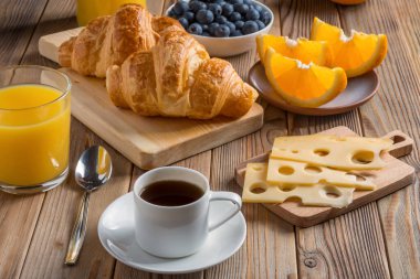 Kruvasan ve kızarmış yumurta ve ahşap zemin üzerinde kahve ve peynir ile Kıtasal Kahvaltı 'nın yakın görüntüsü.