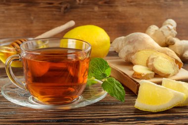 Limonlu zencefilli çay ve ahşap zemin üzerinde cam bardakta nane..