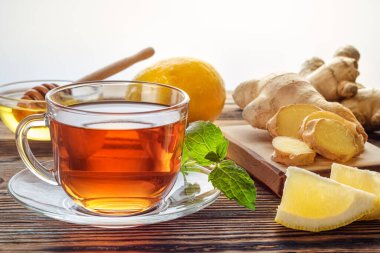 Limonlu zencefilli çay ve ahşap zemin üzerinde cam bardakta nane..