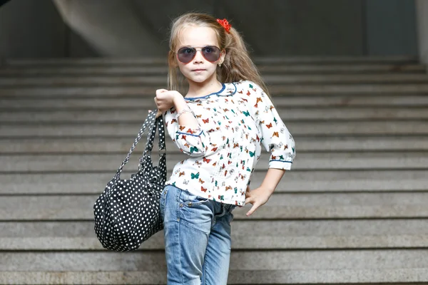 Маленька дівчинка з сумкою в сонцезахисних окулярах позує — стокове фото