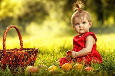 Çimenlerin üzerinde oturan küçük şirin kız