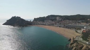 Arkasında küçük bir kasaba olan güzel bir sahil. Su sakin ve gökyüzü berrak.