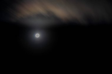 Gökyüzünde bir ay, karanlık bir arkaplanın üzerindedir. Ay sahnedeki tek ışık.