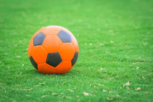 Balón de fútbol naranja en el campo verde — Foto de Stock