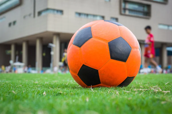 Balón de fútbol naranja en el campo verde — Foto de Stock