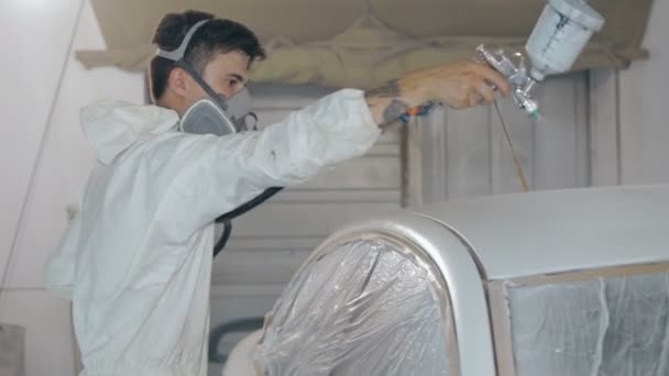Рабочий окрашивает автомобиль в белый цвет — стоковое видео