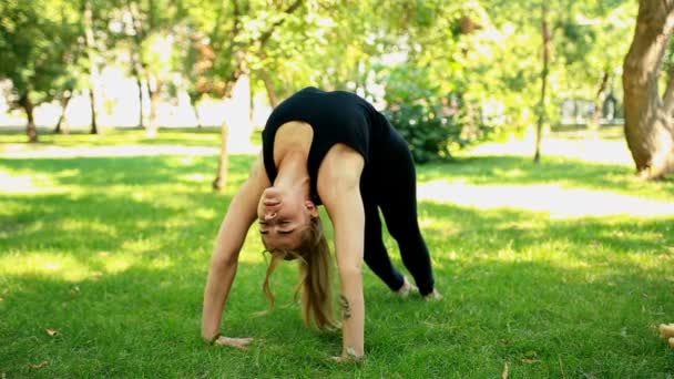 Breda skott ung kvinna göra yoga i parken — Stockvideo