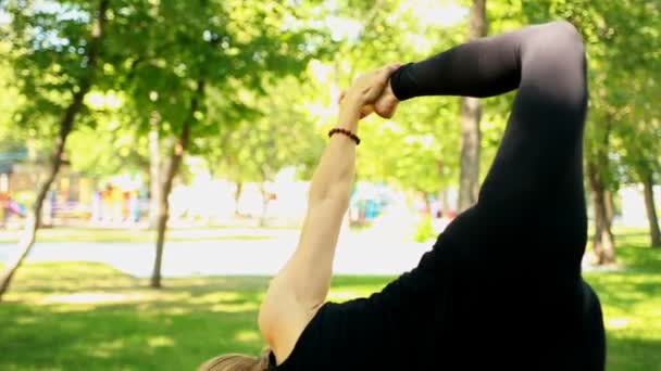 Střední zastřelených mladá žena dělá jógu v parku — Stock video