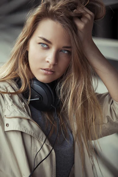 Girl with headphones relies on the grid and looking to the side — Stock Photo, Image