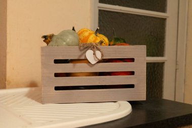 Kırsal bir evin mutfak tabletinde ahşap sepetin içinde dekoratif balkabakları.