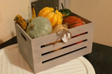 Kırsal bir evin mutfak tabletinde ahşap sepetin içinde dekoratif balkabakları.