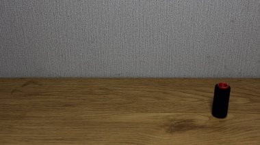 Ahşap bir yüzey üzerinde duran siyah bir makaranın yakın çekimi..