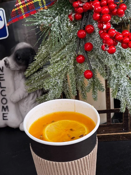 Warm beverage with lemon, surrounded by holiday decorations.