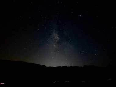 Yıldızlı karanlık gece gökyüzü ve Teide Gözlemevi yakınlarındaki volkanik siluetlerin arkasındaki soluk ufuk ışığı. Yüksek kalite fotoğraf