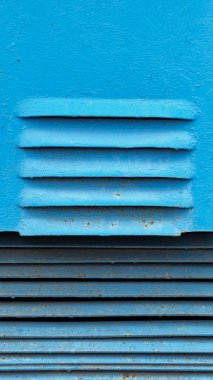 Yatay çizgiler ve dokulardan oluşan mavi bir duvara yakın plan.