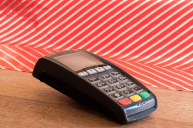 Ahşap masa üzerinde POS terminali kırmızı ve beyaz çizgili arka plan, perakende konsepti