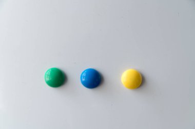 Beyaz yüzeyde üç renkli mıknatıslar, temiz beyaz zemin üzerinde yatay olarak kopyalama alanı ile hizalanmış.