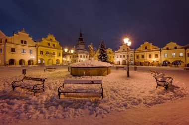 Pelhrimov 2025 'teki Masaryk Meydanı manzarası, sokak lambası, çeşme, temiz kar örtüsü, tarihi evler.